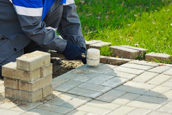 bricklayer-lays-paving-slabs-outside-working-man-performs-landscaping-builder-lays-out-sidewalk-with-stone-blocks